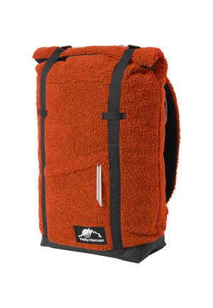 Mochila de tela sherpa texturizada roja con correas negras, bolsillo con cremallera y parche con el logo de Helly Hansen en la esquina inferior delantera.