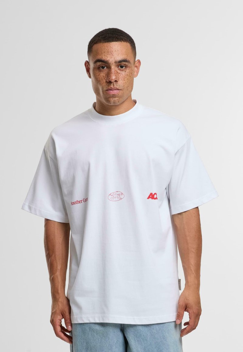 Bílý bavlněný tričko s krátkým rukávem, s červenými logy na hrudi. Kolo výstřih, uvolněný střih a měkká textura.