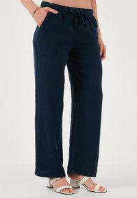 Marineblauwe, wijde broek met een elastische tailleband en een trekkoord, voorzien van zijzakken en een soepele stoftextuur.