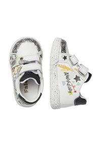 Scarpe bianche in pelle con accenti neri, dotate di cinturini in velcro, scarabocchi colorati e suole puntinate. I design includono stelle e la scritta "ANNIVERSARY."