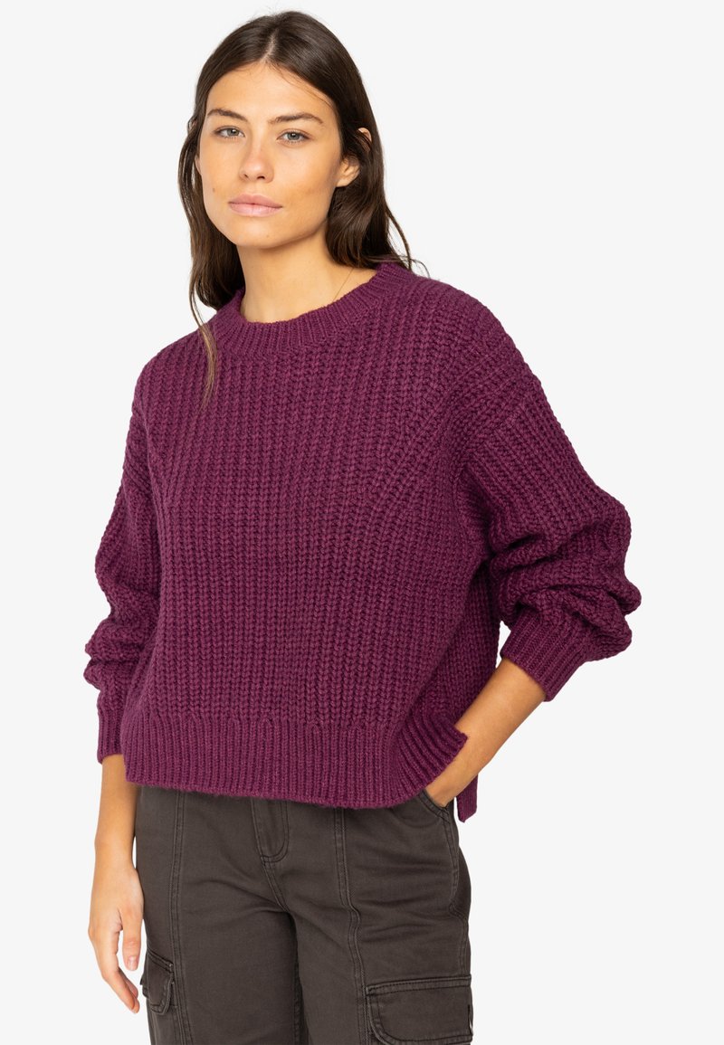 Maglione lavorato a maglia spesso in un profondo viola, con scollatura rotonda, spalle scese e polsini e orlo a coste. Vestibilità casual con tessuto testurizzato.