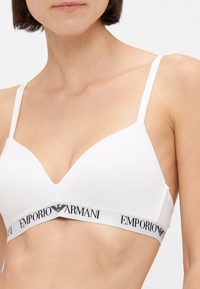 Sutien wireless alb cu un design al cupelor în formă de V, având o textură moale și o bandă elastică cu logo-ul "EMPORIO ARMANI" în negru.