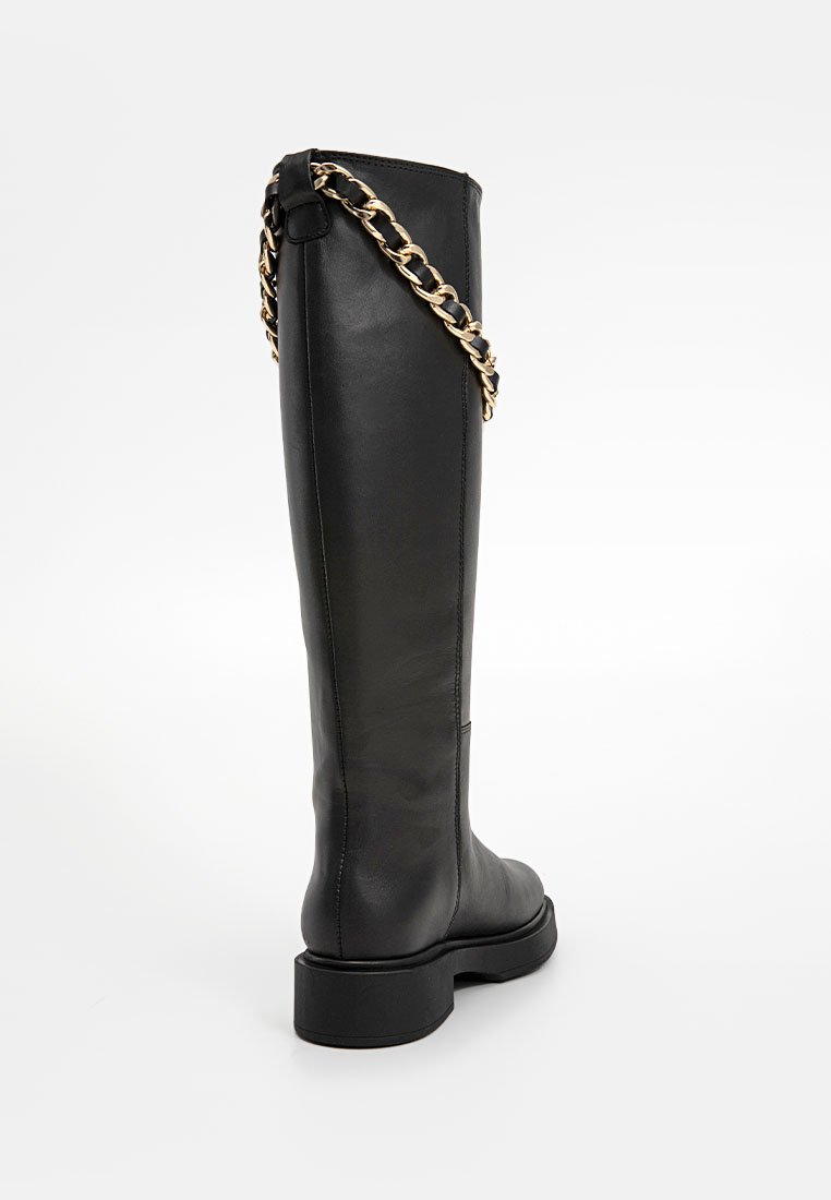 Schwarzlederne Stiefel bis zum Knie mit einer dicken Sohle und einem goldenen Kettenakzent. Glatte Textur, minimalistisches Design und runde Zehen.