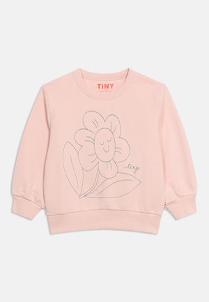 Sweatshirt pour enfant à manches longues de couleur rose clair avec un simple dessin d'une fleur souriante et des feuilles, et le mot « tiny » sur le devant.