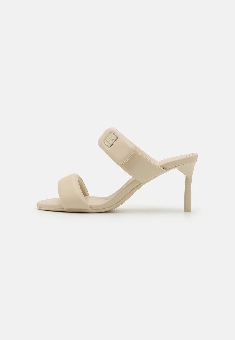 Beige hæler sandaler med en glat imitation læder finish, der har to brede stropper og en slank høj hæl. Diskret logo detalje på stroppen.