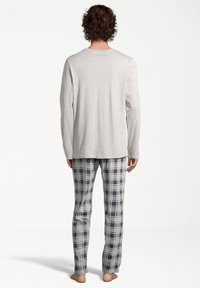 Chemise à manches longues grise associée à un pantalon de pyjama à carreaux dans des tons de bleu et gris. Tissu doux avec une coupe droite et des détails de conception minimaux.