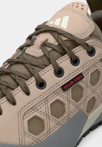 Μπεζ πεζοπορικό παπούτσι με επάνω μέρος από δίχτυ και σουέντ, με εξαγωνικά σχέδια, καφέ κορδόνια, γκρίζα σόλα και κόκκινη λεπτομέρεια λογότυπου "FIVE TEN".
