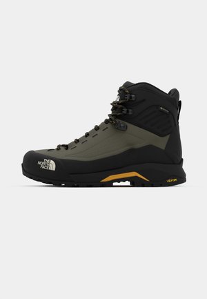 Hiking boot in black and olive green, made from synthetic materials, features a high top, lacing system, and Vibram outsole for traction.