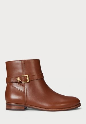 Bottine en cuir marron avec un bout arrondi, détail de boucle sur le côté et un petit talon empilé. Texture lisse avec une couture contrastante.