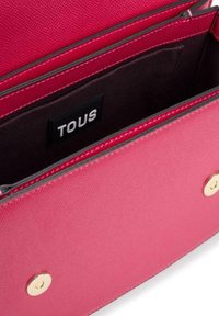 Bolso de mano de tela rosa con un acabado texturizado, cierres de hardware dorado y un interior forrado con una etiqueta de marca negra.