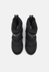 Paire de bottes d'hiver isolées noires avec semelles épaisses et lacets élastiques, vues de dessus sur un fond blanc.