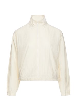 Veste beige clair à manches longues avec col montant et fermeture éclair à l'avant, poignets élastiques et ourlet légèrement raccourci.