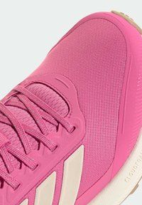 Roze sportschoen met een textuur van mesh aan de bovenkant, contrasterende witte accenten, dunne veters en een lichtgewicht zool met patroon voor grip.