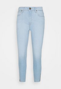 Jeans de mezclilla azul claro con un ajuste slim, diseño de cinco bolsillos, cierre de botón en la parte frontal y cremalleras laterales negras contrastantes en el dobladillo.
