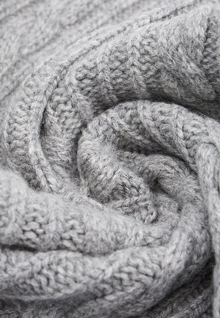 Miękka, gruba szara wełniana dzianina ściśle zwinięta w spiralę, ukazująca szczegółowe, teksturowane ściegi i przytulne włókna.