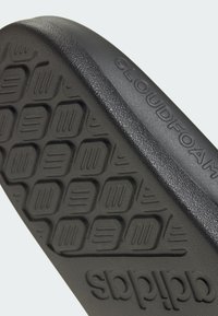 Black rubber shoe sole with textured grip pattern and "CLOUDFOAM" embossed detail. Slightly curved shape for comfort.