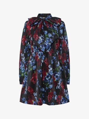 Vestido floral com fundo preto, apresentando flores vermelhas, azuis e verdes. Mangas longas e um grande detalhe de gola em laço.