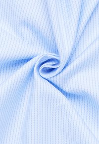 Lichtblauwe stof met subtiele diagonale strepen. Gladde textuur, lichtgewicht materiaal en een wervelende opstelling creëren dynamische plooien.