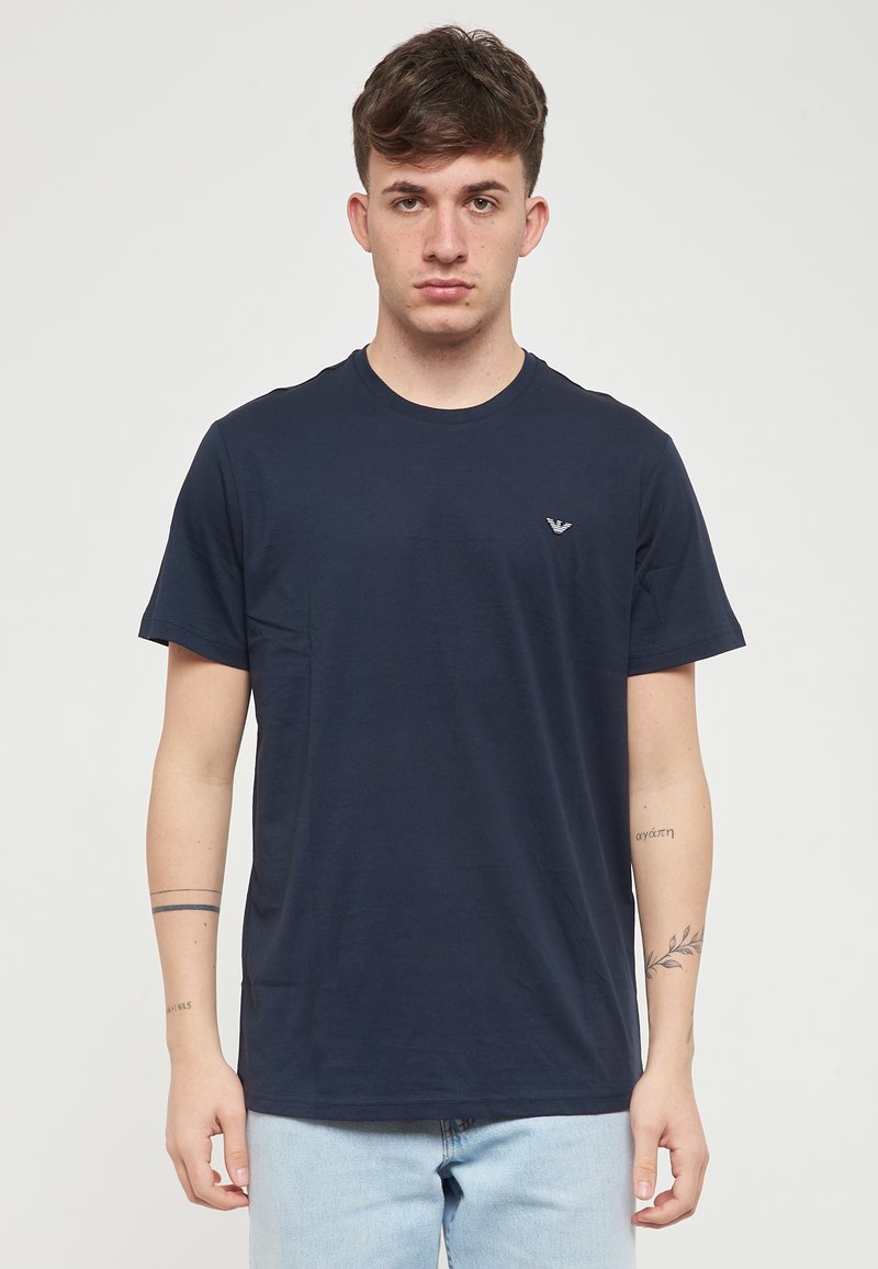 T-shirt à manches courtes bleu marine en coton avec un col rond, arborant un petit logo sur la poitrine gauche et une coupe régulière.