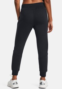 Black sweatpants with a slim fit, elastic waistband, and ribbed cuffs. Features side pockets and smooth fabric texture.