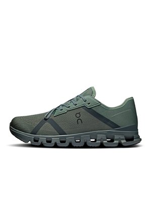 Chaussure de sport verte avec tige en mesh, finition texturée, bandes plus foncées contrastantes et semelle rembourrée avec un design segmenté distinct.