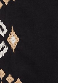 Juodas audinys su įmantriomis smėlio ir baltos spalvos siuvinėjimo detalėmis, vaizduojančiomis deimantų ir kreivų linijų raštus. Tekstūra atrodo minkšta ir išsami.