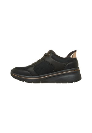 Zapato deportivo negro con tejido de malla, suela gruesa, pestaña metálica en color oro rosa y detalles a juego en los cordones y el borde de la suela.