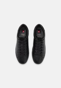 Baskets en cuir noir avec un bout rond, des lacets plats et des accents texturés au niveau du talon. Dotées d'une semelle intérieure marquée et d'un design minimaliste.