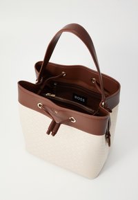 Borsa a tracolla beige e marrone con superficie texturizzata, due manici marroni, tasche interne e dettagli in metallo dorato. Presenta una chiusura con cordoncino.