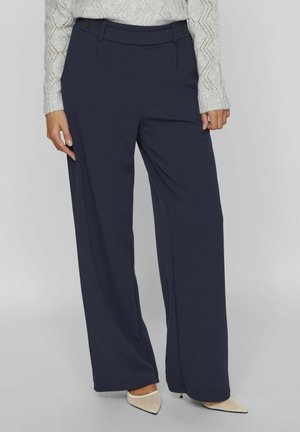 Pantalons large bleu marine en tissu doux, présentant un devant plat avec deux boutons et des poches latérales. Texture lisse, design ajusté.