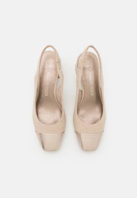 Beezilised slingback kontsad suletud varbaga, millel on metallik kuldne kaan ja pehme nahast viimistlus, esitades klassikalise disaini ja tekstuuri.