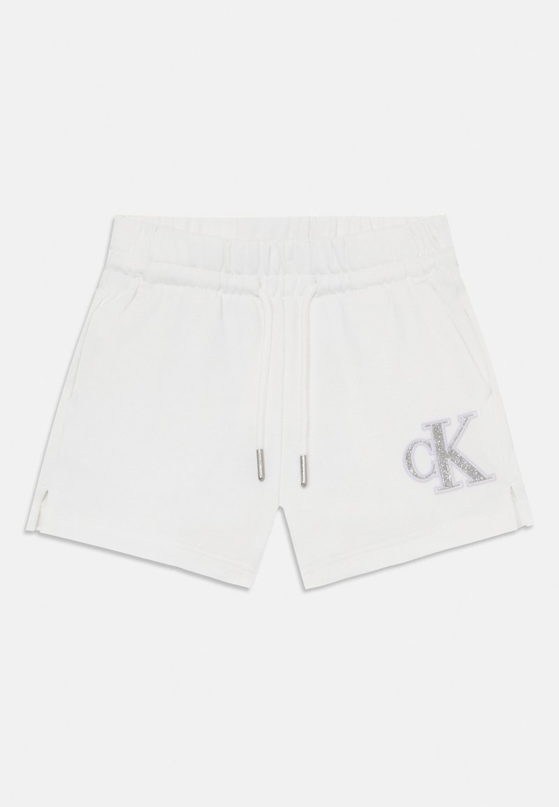 Shorts en coton blancs avec une taille élastique et un cordon de serrage, présentant des fentes sur les côtés et un logo en paillettes argentées sur la jambe gauche.