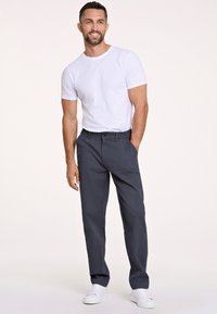 Granatowe bawełniane spodnie o slim fit, z zapięciem na guzik i kieszeniami bocznymi, w połączeniu z gładką białą koszulką z okrągłym dekoltem i białymi trampkami.