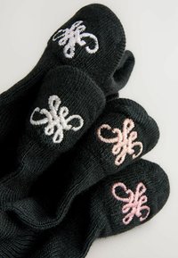 Quatre gants noirs en tricot avec des motifs floraux symétriques brodés en blanc et rose sur les doigts, sur un fond clair uni.