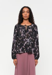 Schwarze Bluse mit lila und grauem abstraktem Muster, runder Ausschnitt, Bindedetail in der Mitte und langen Ballonärmeln, aus leichtem Material gefertigt.