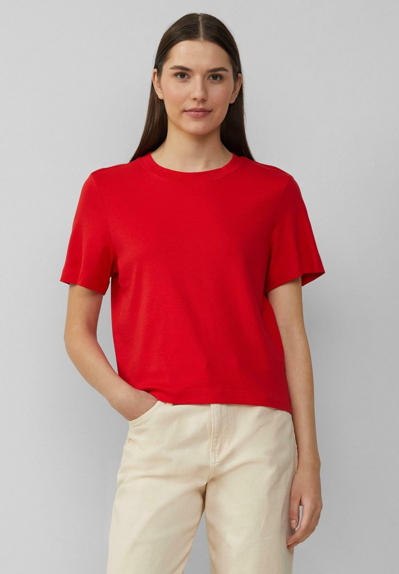 Rode korte mouw t-shirt van zachte katoenen stof met een ronde hals; heeft een relaxte pasvorm en een minimalistisch ontwerp tegen een neutrale achtergrond.