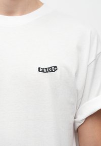 Λευκό βαμβακερό T-shirt με μικρό μαύρο κεντημένο λογότυπο "VOLCOM" στην επάνω αριστερή πλευρά, κοντά μανίκια και άνετη εφαρμογή.