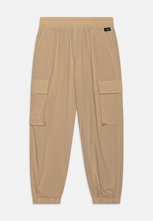 Pantalon cargo beige avec taille élastique et poignets élastiques, poches latérales, poches à rabat sur les cuisses, et une petite étiquette de marque noire près de la taille.