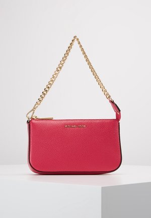 Petit sac à main en cuir rose texturé avec une bandoulière chaîne dorée et une fermeture éclair, posé sur une surface blanche.