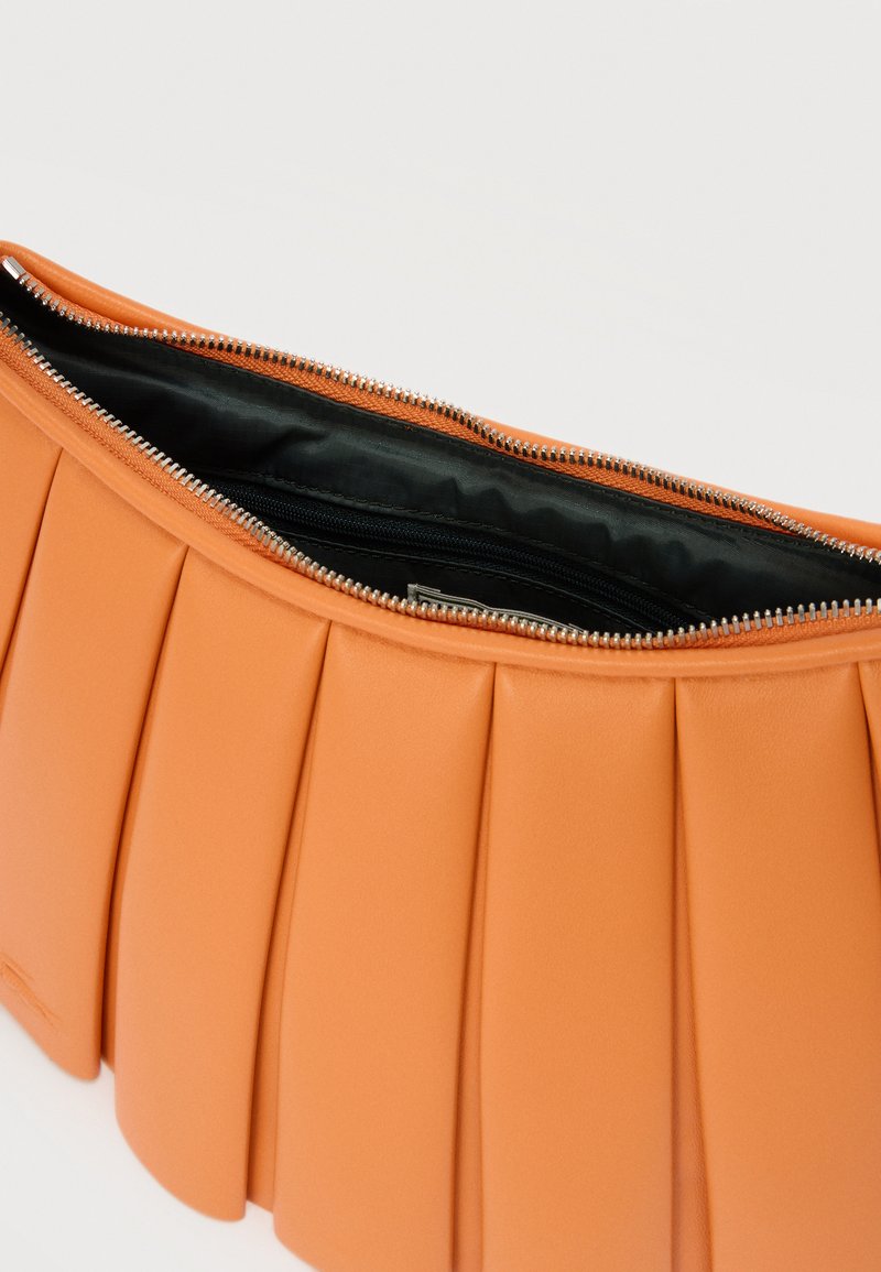 Orange pleated leather clutch bag with a silver zipper partially open, showing black fabric lining and inner zippered pocket.