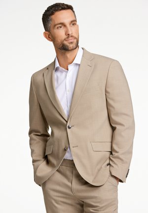 Beiges Blazer- und Hosen-Set, taillierte Passform, Ein-Knopf-Verschluss, Reverskragen, kombiniert mit einem weißen Hemd mit Knöpfen, glatte Stoffstruktur.