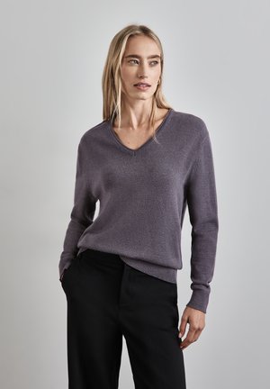 V-hals sweater i blødt, afdæmpet lilla strik, med lange ærmer og ribkant. Sammen med sorte bukser, præsenteret mod en neutral baggrund.