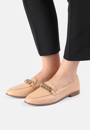 Beige læder loafers med firkantet tå, der har en guldkæde-accent på vampsen og en lav, trælignende hæl. Bæres med sorte bukser.