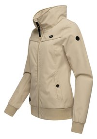 Béžová bunda s vysokým golierom, zipsom vpredu, dvoma bočnými vreckami a rebrovanými manžetami. Obsahuje čierne gombíky na rukávoch a na hrudi. Hladká látka.