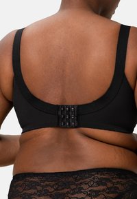 Černá podprsenka s širokými ramínky a zapínáním na háček a oko na zadní straně, vyrobená z hladkého materiálu s jemnou texturou.