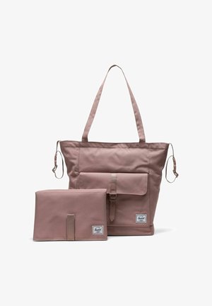 Sac fourre-tout mauve avec poche avant à boucle et sangles amovibles, accompagné d'une pochette pliante mauve assortie avec boucle, les deux utilisant des écussons de logo de marque.