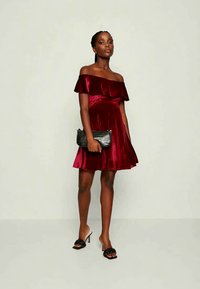 Vestido bordeaux sem alças com corpete ajustado e saia rodada, feito de tecido de cetim; combinado com uma clutch preta texturizada e sandálias pretas.