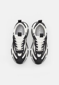 Black and white sneakers featuring a mesh upper with synthetic overlays, laces, padded collar, and a chunky rubber sole.