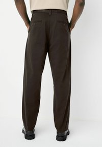 Dark brown trousers with a straight leg design, featuring two back pockets with buttons, made from a durable fabric.