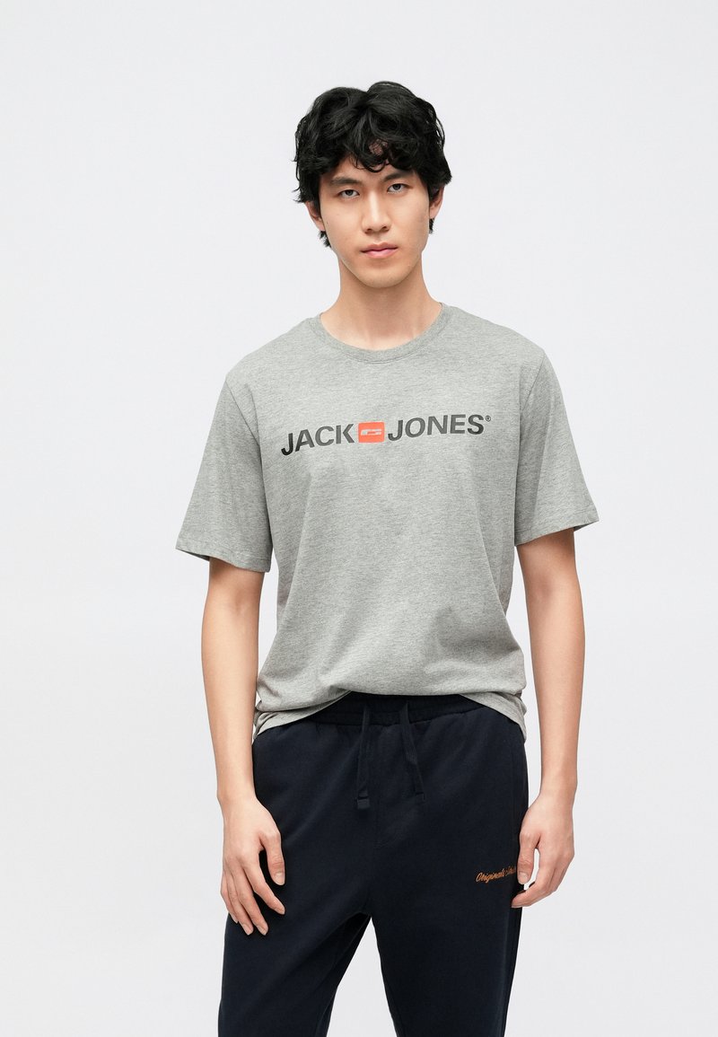 Grå bomull T-skjorte med svart "JACK & JONES"-logo og oransje aksent. Kombinert med mørkeblå joggebukser med subtil brodering.